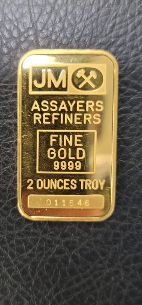 A two-ounce fine gold bullion bar stamped 9999 resting on a black leather surface